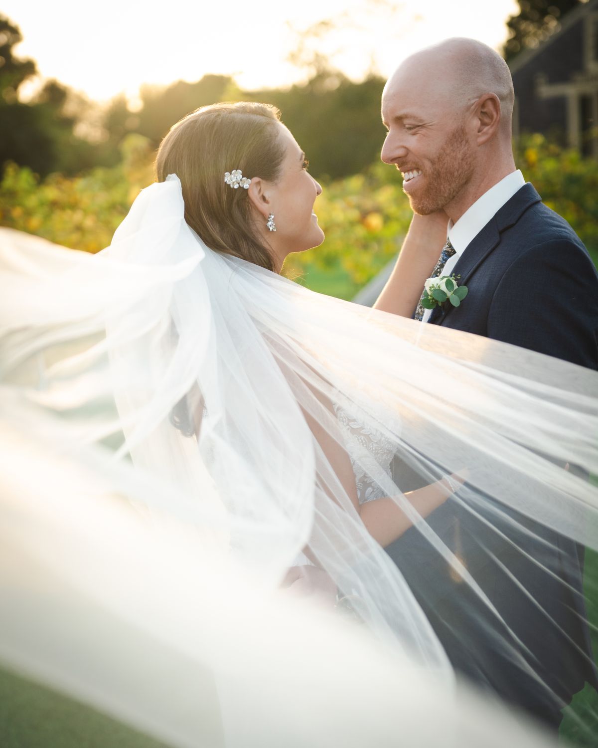 Bride and groom at golden hour beneath a flowing veil